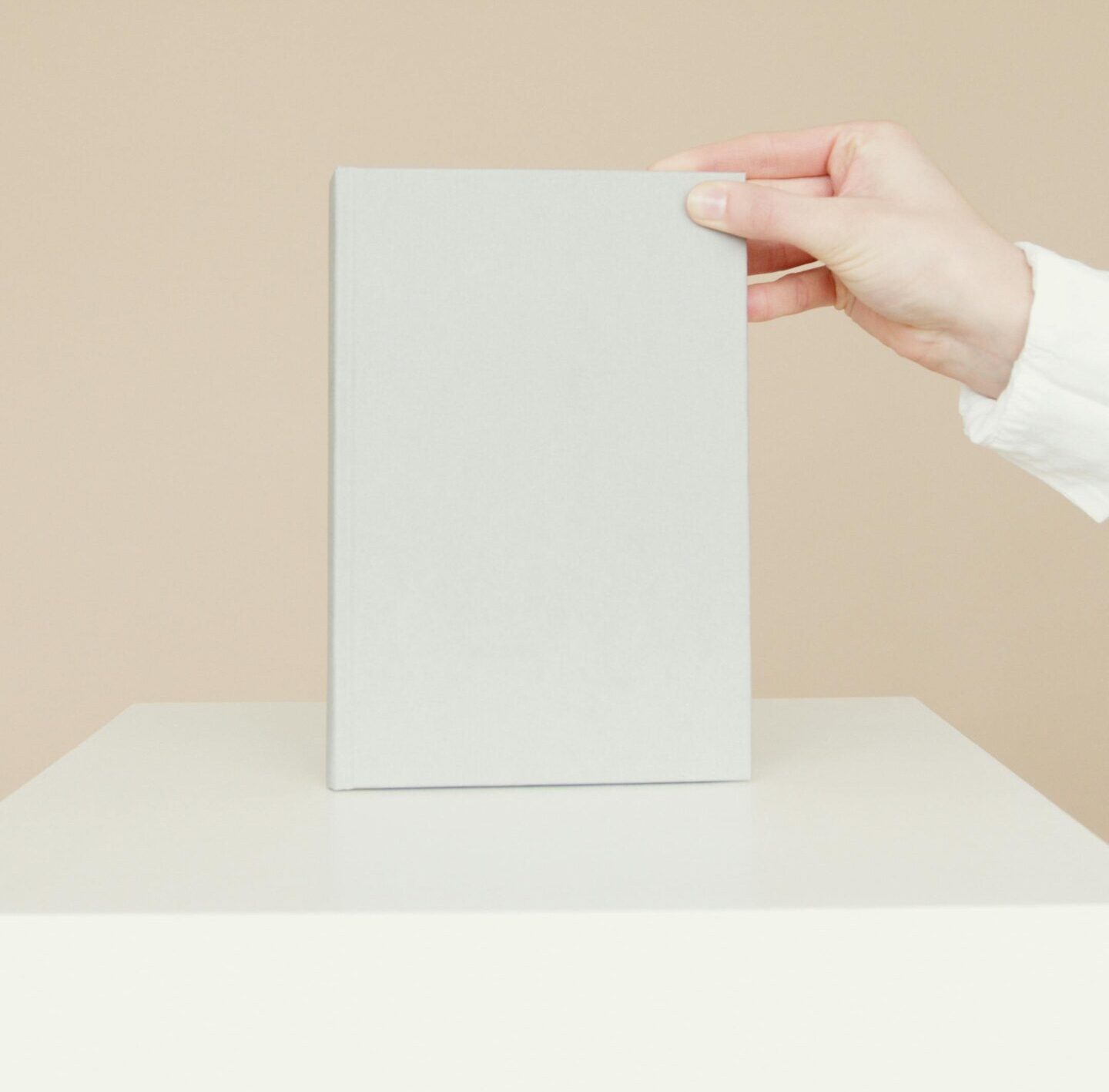 Simple minimalist image of a blank book being held by a person's hand, ideal for branding.